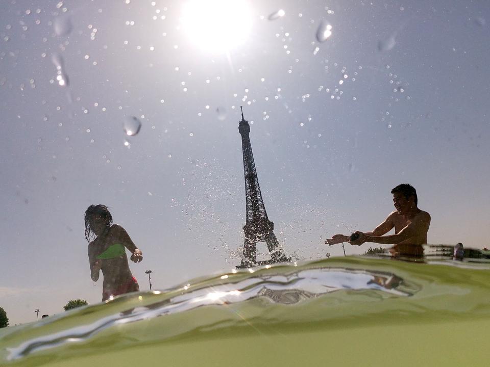 People cool off at the Trocadero Fountains next to the Eiffel Tower in Paris on July 25, 2019.