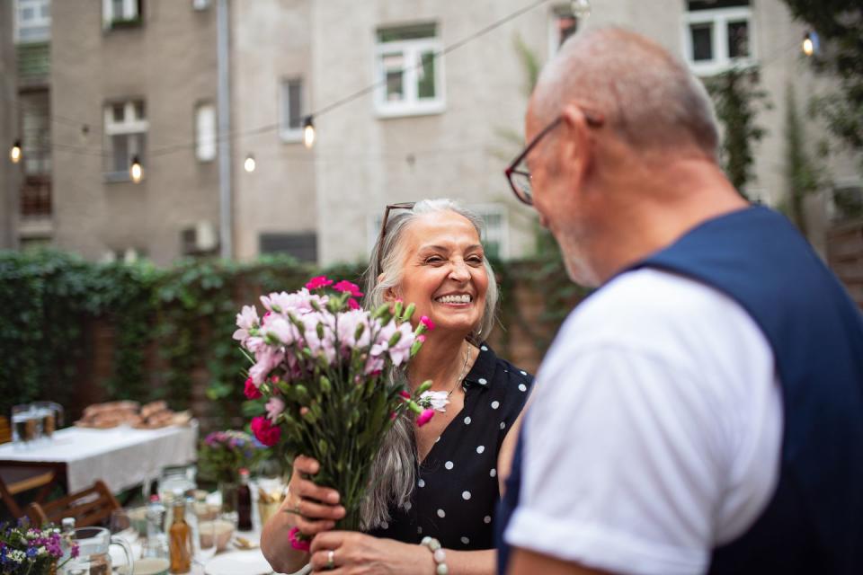 happy senior woman getting bouquet from her husband outdoors in garden
