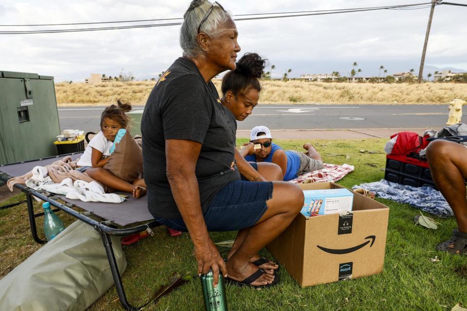 Family members wait by the side of a road after being forced from their home