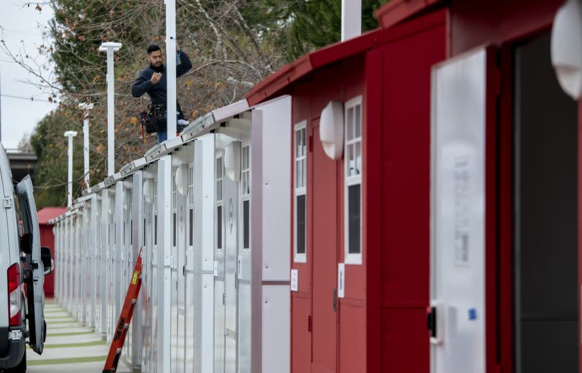 NORTH HOLLYWOOD, CA - FEBRUARY 01: Luis Guzman installs a security camera at a new 'Tiny Homes' community on Monday, Feb. 1, 2021 in North Hollywood, CA. The 10ft by 10ft Pallet Shelter units have two beds as well as heating and air conditioning. The site will also have food and laundry facilities when work is completed. (Brian van der Brug / Los Angeles Times)