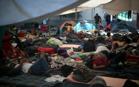 Migrants, part of a caravan of thousands from Central America trying to reach the United States, rest in a temporary shelter in Tijuana - Credit:  HANNAH MCKAY/REUTERS