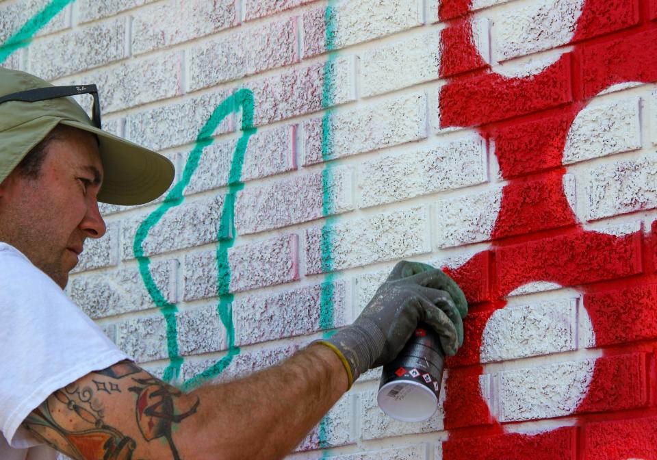 Artist Greg Pennison works on his mural outside the Potter's Printing building on Pocasset Street in Fall River, on July 22, 2022.