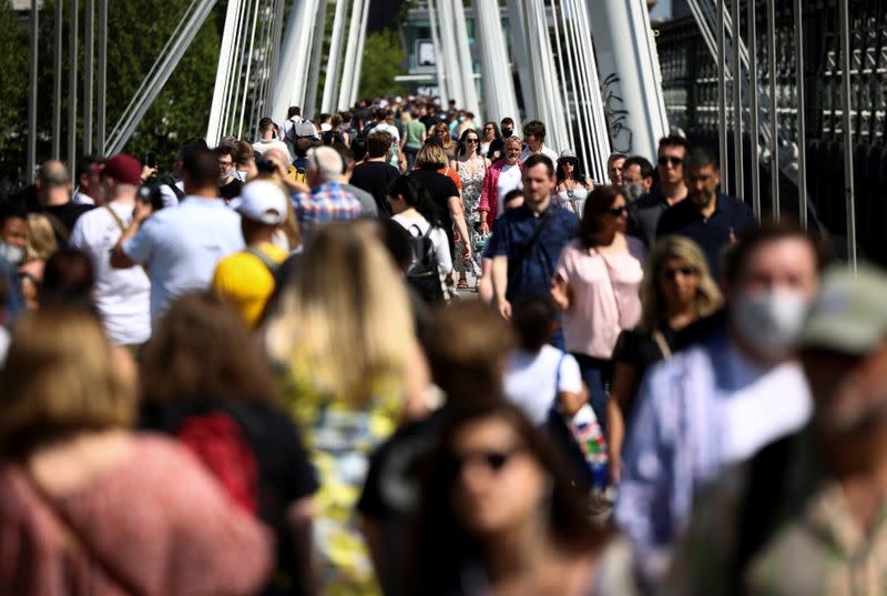 FILE PHOTO: People walk across Millennium Bridge during sunny weather, amid the coronavirus disease (COVID-19) outbreak, in London