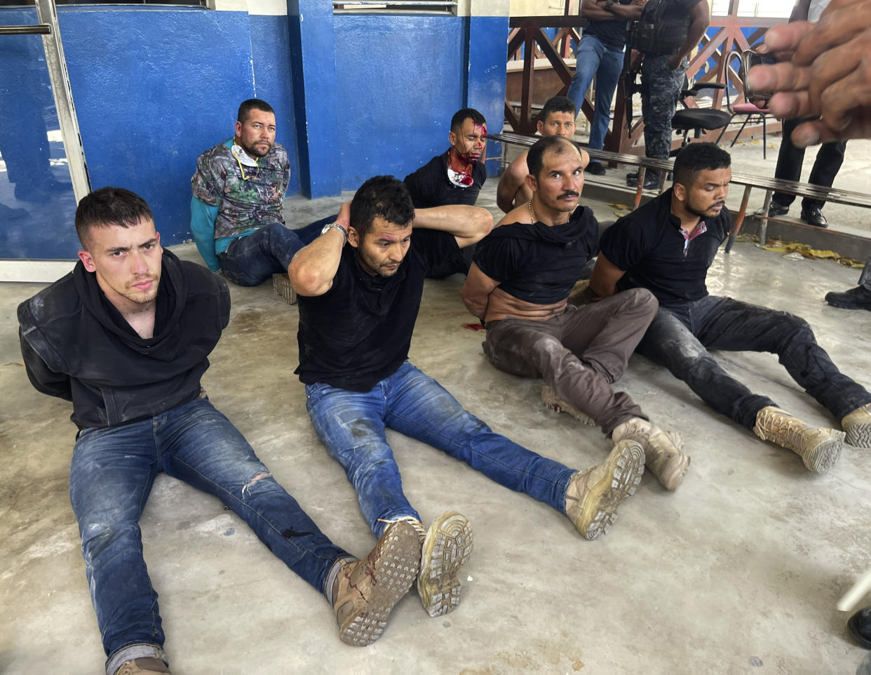 Suspects in the assassination of Haiti's President Jovenel Moise sit on the floor handcuffed after being detained, at the General Direction of the police in Port-au-Prince, Haiti, Thursday, July 8, 2021. A Haitian judge involved in the murder investigation said that President Moise was shot a dozen times and his office and bedroom were ransacked. (AP Photo/Jean Marc Hervé Abélard)