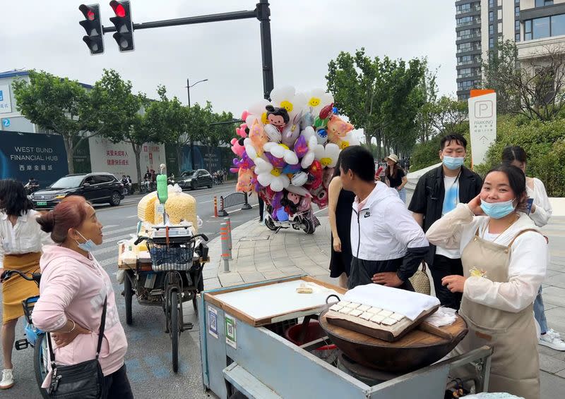 Wang Chunxiang waits for customers as she sells steamed sweet rice cake on a wheel cart among other street vendors in Shanghai