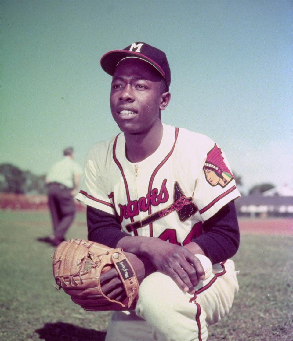 Milwaukee Braves slugger Hank Aaron kneels in the outfield before a game, June 1957. Baseball's untainted home run king died on Jan. 22 at 86.