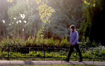 A pedestrian with a face mask enjoys the evening sun during his activity in a park in London, Thursday, April 23, 2020, during the COVID-19 lockdown. People are encouraged to take some exercise while adopting social distancing measures to limit the spread of COVID-19 coronavirus. (AP Photo/Frank Augstein)