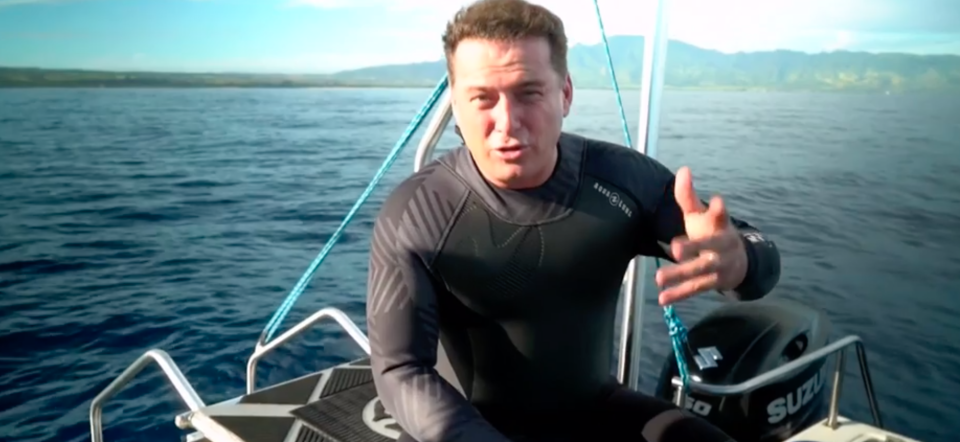 Karl Stefanovic sits on a boat in a wetsuits