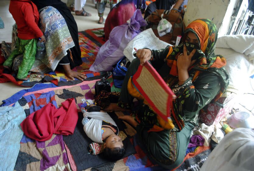 A woman fans her child as displaced families take refuge at a relief camp in Dadu district of Sindh Province in southern Pakistan, Sunday, Aug. 28, 2022. Army troops are being deployed in Pakistan's flood affected area for urgent rescue and relief work as flash floods triggered after heavy monsoon rains across most part of the country lashed many districts in all four provinces. (AP Photo/Pervez Masih)