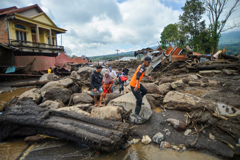 Locals walk in an area affected by heavy rain brought flash floods and landslides as they are evacuated in Agam