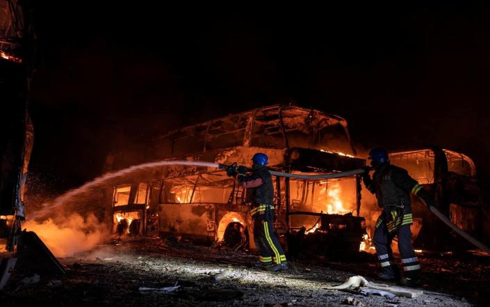 Firefighters work at a site of a vehicle parking area damaged by remains of Russian missiles in Kyiv - STATE EMERGENCY SERVICE OF UKRAINE/via REUTERS