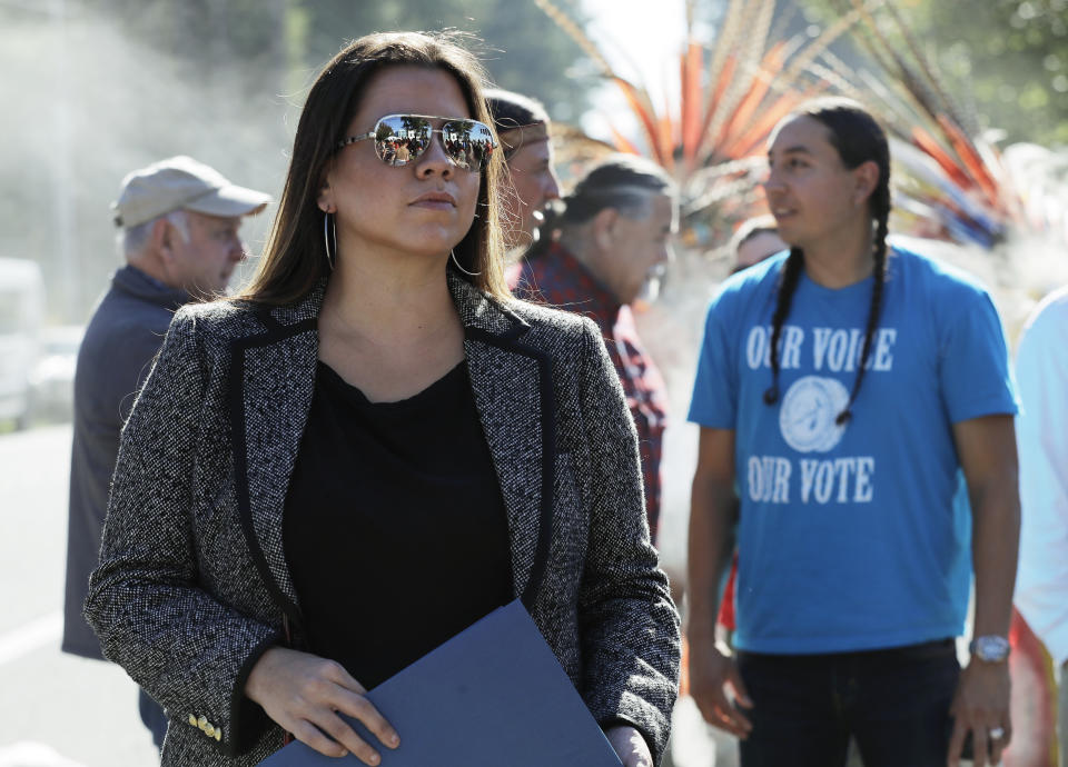 CORRECTS TO WILLIS’ TRIBE REQUIRES 1/4 NATIVE AMERICAN BLOOD, AND A GRANDPARENT OR PARENT TO BE ENROLLED IN THE TRIBE - In this Oct. 17, 2018 photo, Nicole Willis, left, a member of the Confederated Tribes of the Umatilla Reservation who lives in Seattle, listens to speakers at a rally in Lacey, Wash. Elizabeth Warren's spat with Donald Trump over Warren's Native American heritage has brought global attention to what it means to be Native American. Willis believes being Native American means her family is part of a distinct, interconnected community that has existed since ancient times. Willis’ tribe requires 1/4 Native American blood, and a grandparent or parent to be enrolled in the tribe but she said “theoretically, it shouldn’t matter.”(AP Photo/Ted S. Warren)