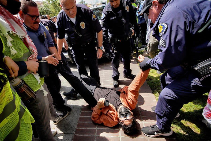 A University of Southern California protester is detained by USC Department of Public Safety officers during a pro-Palestinian occupation at the campus’ Alumni Park on Wednesday, April 24, 2024 in Los Angeles. (AP Photo/Richard Vogel)