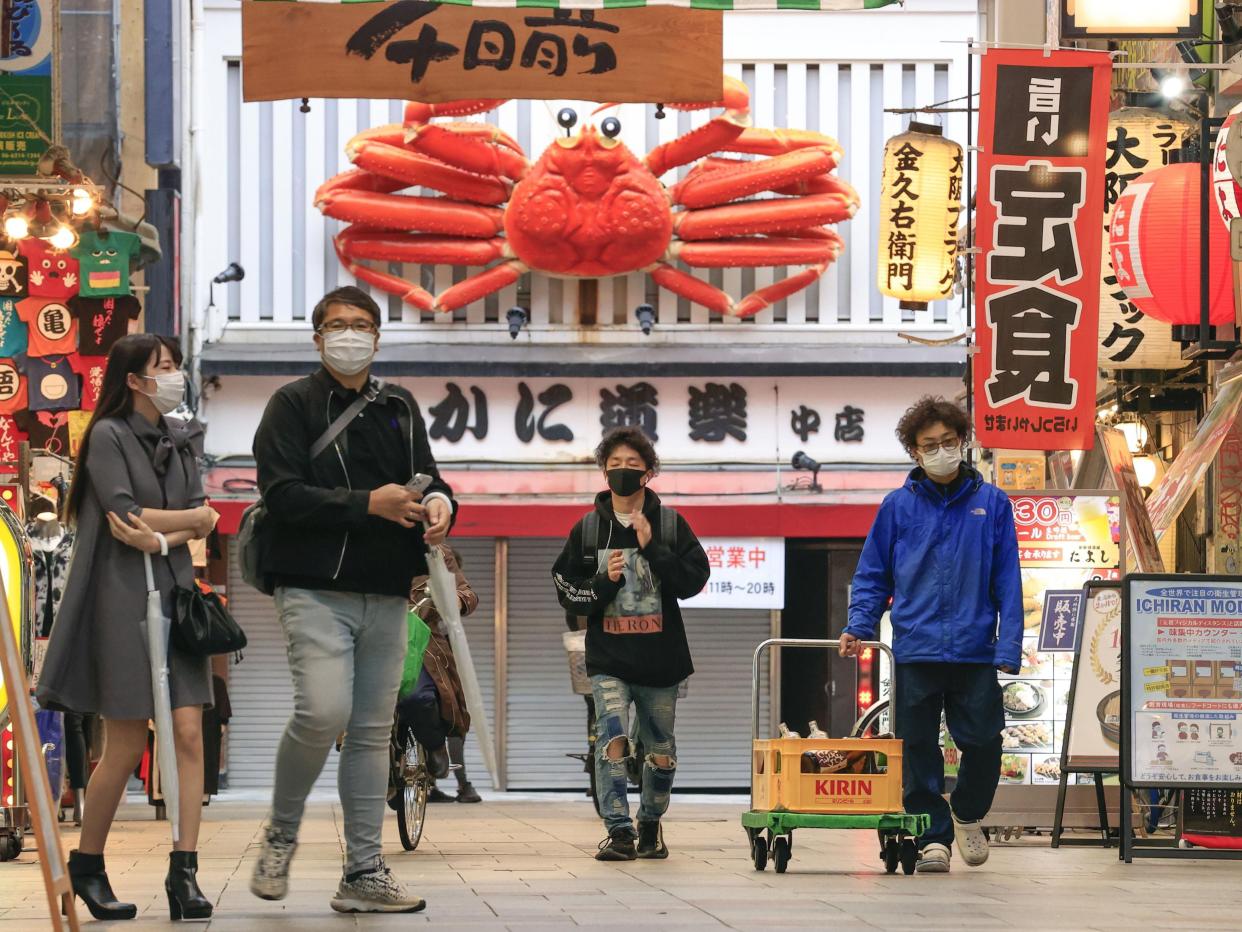 People wearing a face mask walk through downtown Osaka, western Japan, on Friday.