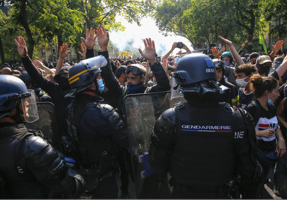 Yellow vest protesters wearing protective face masks as precaution against the conoravirus holds up their hands during a march in Paris, Saturday, Sept. 12, 2020. Activists relaunched France's yellow vest movement Saturday after the disruptive demonstrations against Emmanuel Macron's presidency and perceived elitism tapered off during the coronavirus pandemic.(AP Photo/Michel Euler)