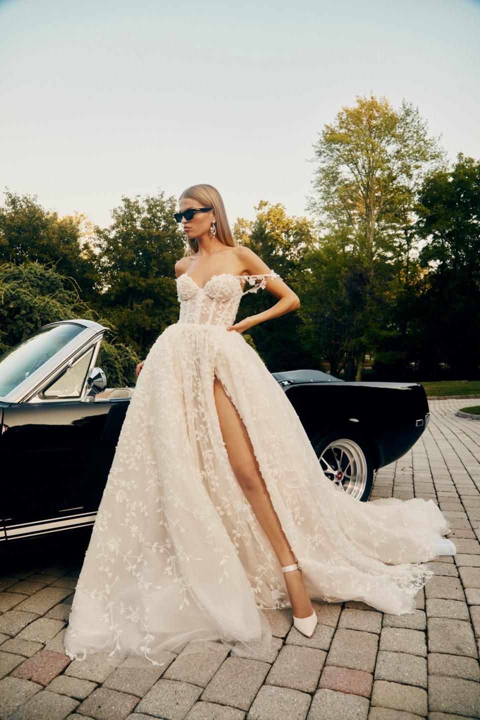 A bride stands in front of a convertible.