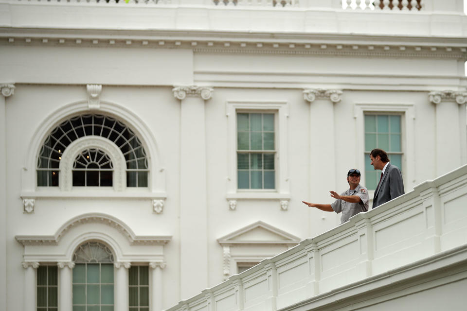 National Park Service workers stand on the roof of the West Wing.