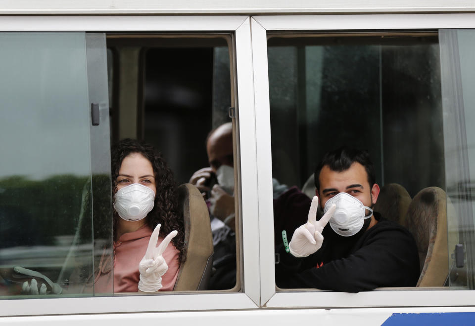 Lebanese passengers who were stuck in Saudi Arabia flash victory signs, as they sit in a bus after arriving to Rafik Hariri Airport, in Beirut, Lebanon, Sunday, April 5, 2020. Passengers who arrived in Lebanon from abroad will be transferred by buses to hotels where they'll get tested for coronavirus. Once the results are known, those who test negative can go home while anyone who tests positive will be referred to local hospitals. A jet carrying more than 70 Lebanese citizens, who had been stuck in Saudi Arabia after Beirut's international airport closed nearly three weeks ago to limit the spread of coronavirus, arrived in Lebanon Sunday. (AP Photo/Hussein Malla)