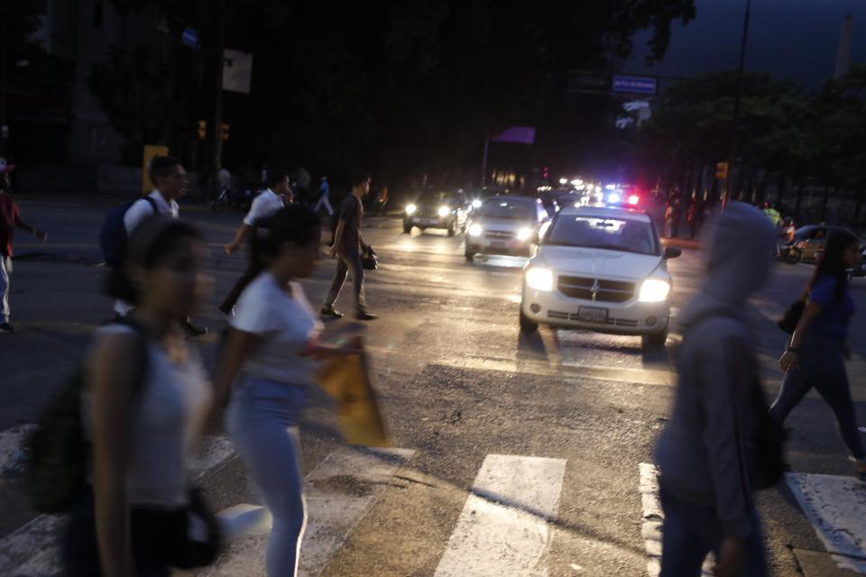 People cross a street during a blackout in Caracas, Venezuela, Monday, July 22, 2019. The lights went out across much of Venezuela Monday, reviving fears of the blackouts that plunged the country into chaos a few months ago as the government once again accused opponents of sabotaging the nation's hydroelectric power system. (AP Photo/Ariana Cubillos)