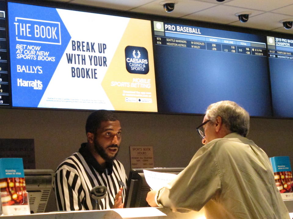 This Sept. 5, 2019 photo shows a gambler making a sports bet at Bally's casino in Atlantic City N.J. Participants in a national sports betting conference on Dec. 1, 2020, agreed that huge holes in state budgets due to the coronavirus outbreak, and the demonstrated eagerness of fans to bet on sports are likely to spur a further expansion of sports betting and online casino gambling in the U.S. (AP Photo/Wayne Parry)