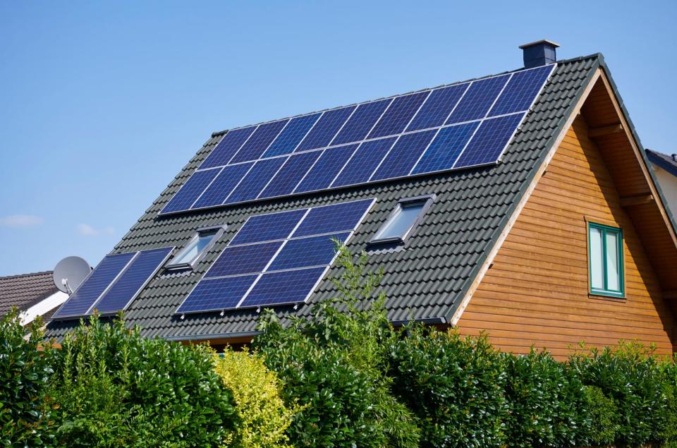 A-wood-house-has-solar-panels-along-the-black-tiled-roof.