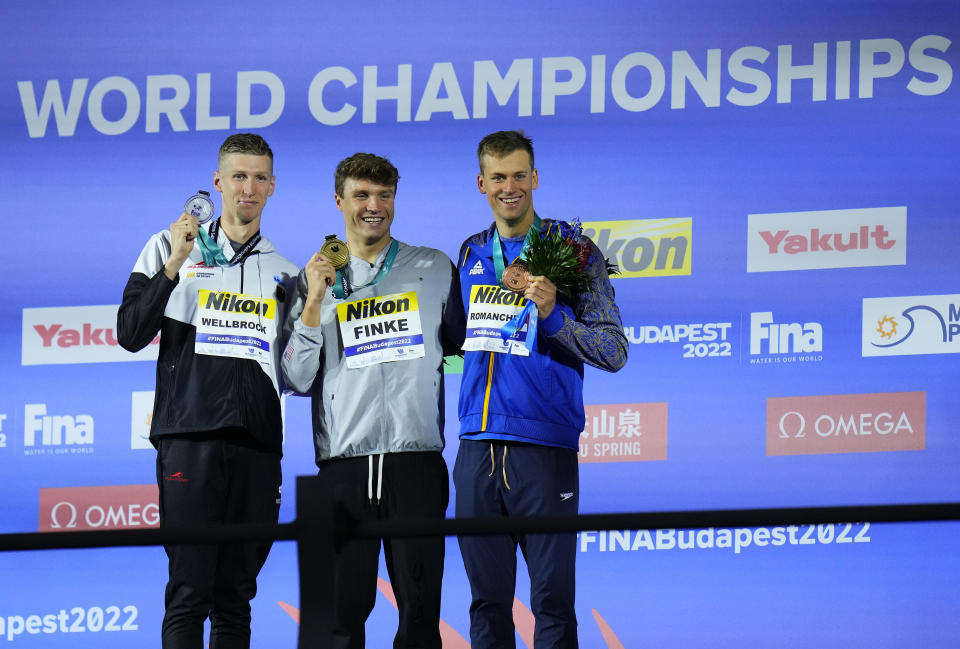 Florian Wellbrock of Germany, Bobby Finke of the United States, Mykhailo Romanchuk of Ukraine, from left to right, pose with their medals after the Men 800m Freestyle final at the 19th FINA World Championships in Budapest, Hungary, Tuesday, June 21, 2022. (AP Photo/Petr David Josek)