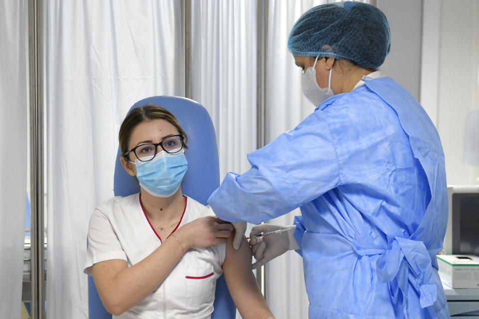 Mihaela Anghel, a Romanian nurse, gets the first COVID-19 vaccine administered in the country in Bucharest, Romania, Sunday, Dec. 27, 2020. Anghel is the nurse who registered and processed Romania's first official COVID-19 patient, on Feb. 27, 2020. (AP Photo/Andreea Alexandru)