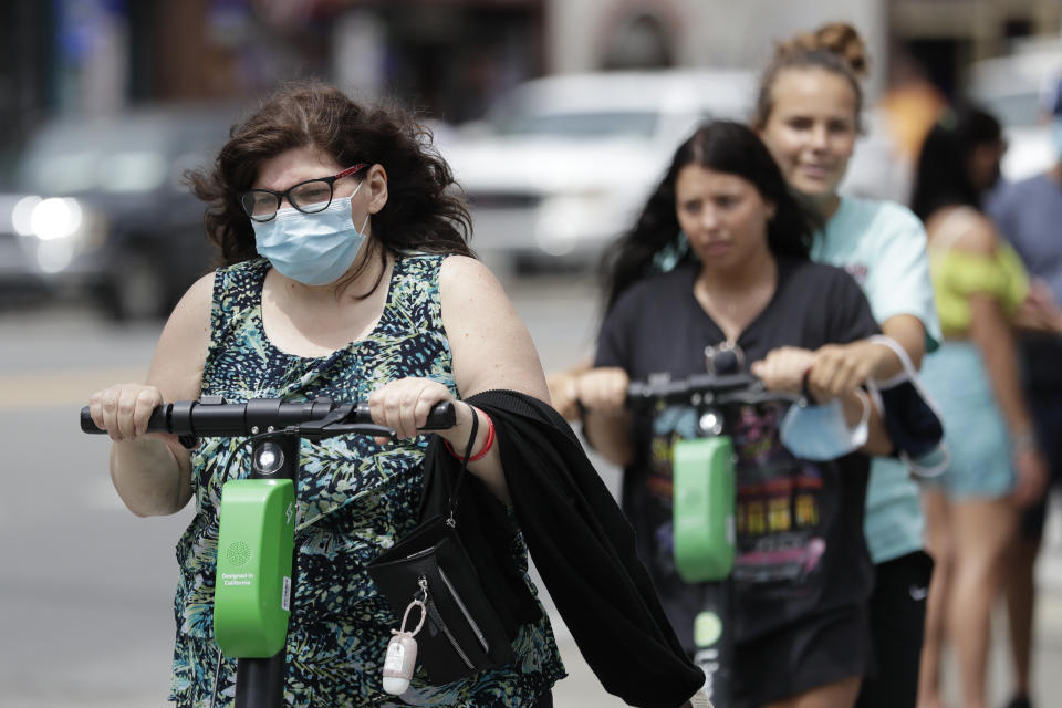 A woman wears a mask as she rides a scooter Tuesday, June 30, 2020, in Nashville, Tenn. The Nashville Health Department has put in place a mask mandate to help battle the spread of the coronavirus. (AP Photo/Mark Humphrey)