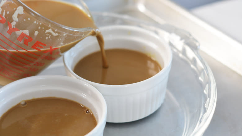 Custard mixture being poured into ramekins