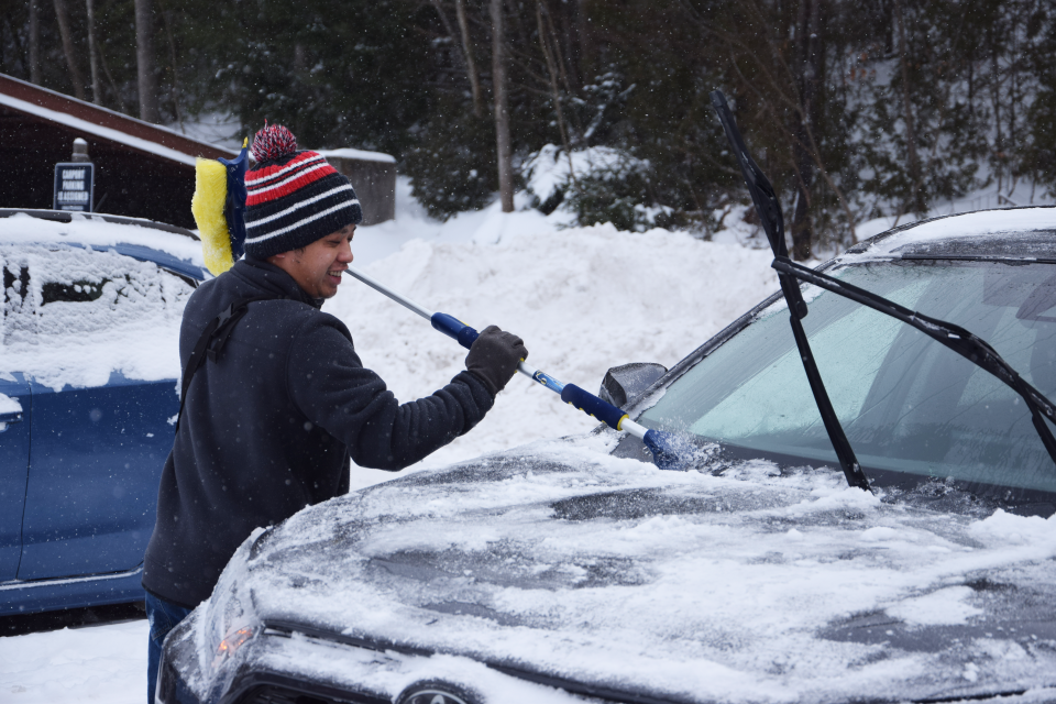 Jeffrey Yang scrapes ice and snow off his car in Petoskey following a winter storm on Jan. 13, 2024.
