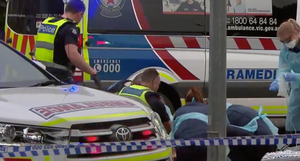 Paramedics are shown tending to someone on the ground next to an ambulance at the scene. Source: Nine News