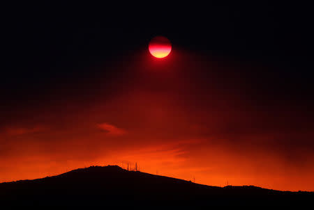 The sun sets under a cloud of smoke caused by a wildfire fanned by strong winds on the island of Evia, in Athens, Greece, August 12, 2018. REUTERS/Yannis Behrakis/Files