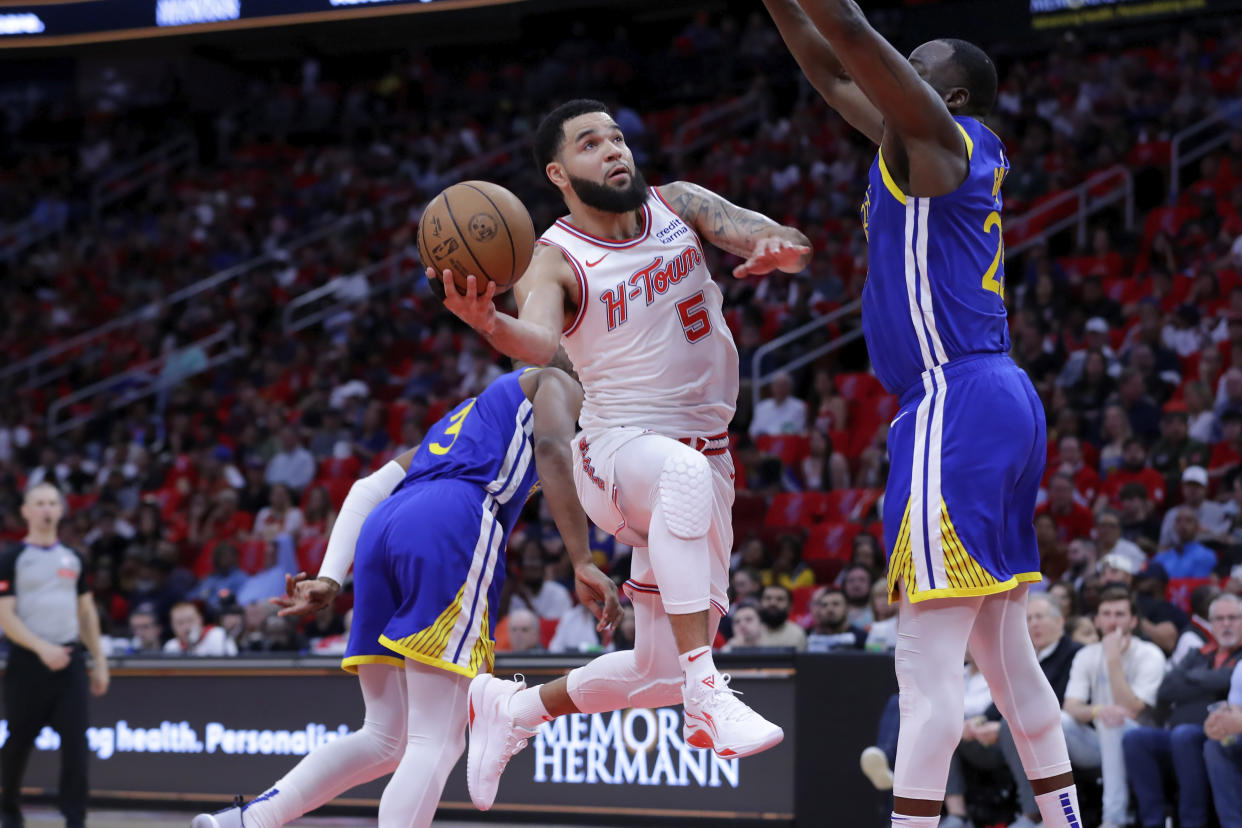Houston Rockets guard Fred VanVleet (5) lays up a shot between Golden State Warriors guard Chris Paul, left, and forward Draymond Green, right, during the first half of an NBA basketball game Thursday, April 4, 2024, in Houston. (AP Photo/Michael Wyke)