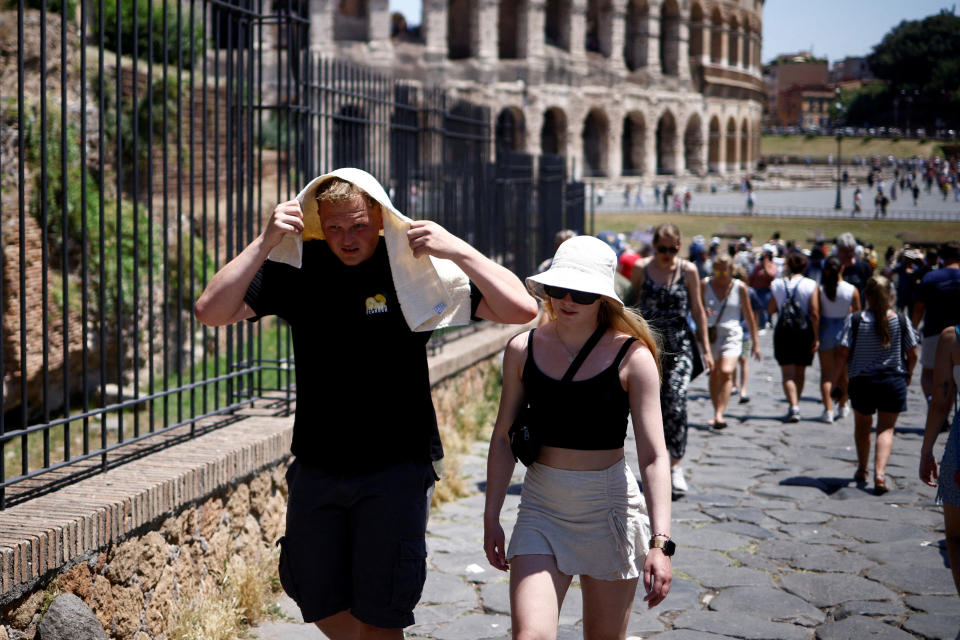 A man shelters from the sun with a towel near the Colosseum during a heatwave across Italy, in Rome, Italy July 11, 2023. REUTERS/Guglielmo Mangiapne