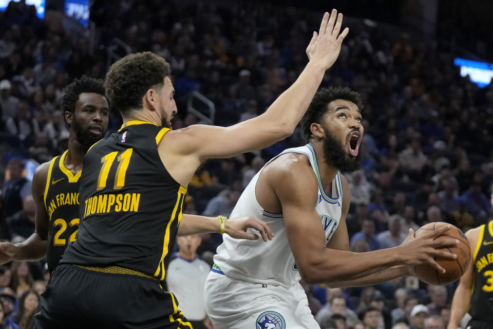 Minnesota Timberwolves center Karl-Anthony Towns, right, shoots against Golden State Warriors guard Klay Thompson (11) during the first half of an NBA basketball game in San Francisco, Sunday, Nov. 12, 2023. (AP Photo/Jeff Chiu)