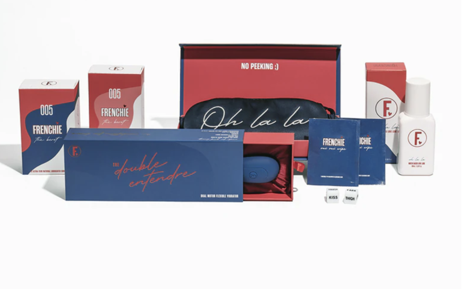 L'Ultimate Lovers Kit, $160 is shown unpacked on a white background near its navy and red packaging, including a vibrator, lube, sachets, condoms and dice