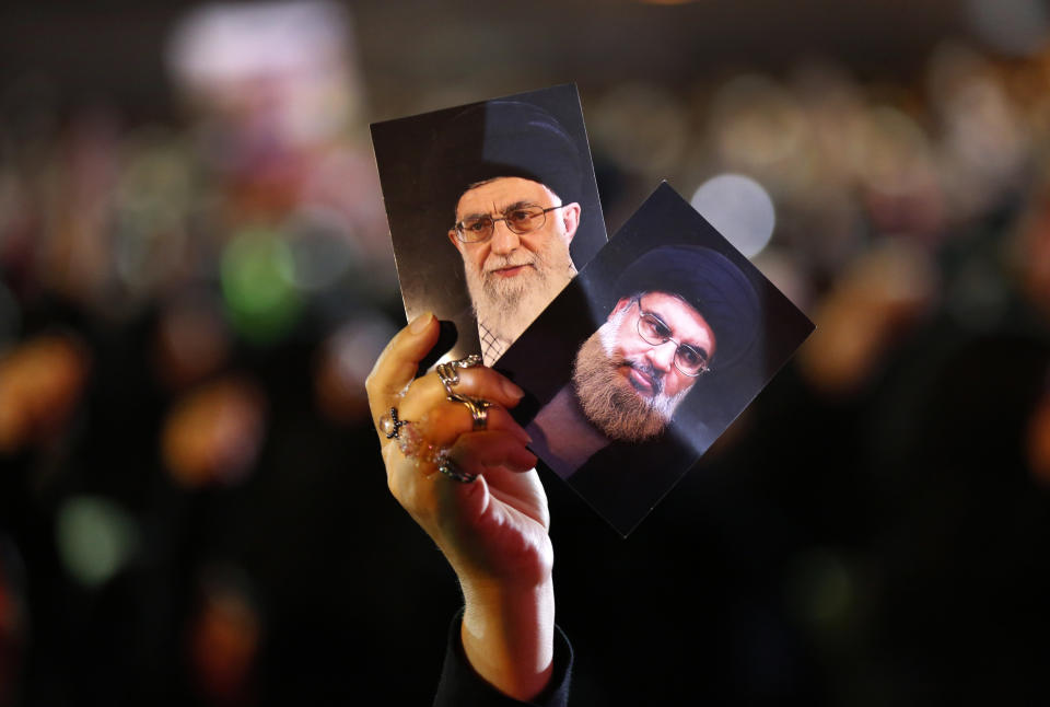 A Hezbollah supporter holds up portraits of Hezbollah leader Sheikh Hassan Nasrallah, right, and Iran's supreme leader Ayatollah Ali Khamenei, left, during activities to mark the ninth of Ashura, a 10-day ritual commemorating the death of Imam Hussein, in a southern suburb of Beirut, Lebanon, Wednesday, Sept. 19, 2018. Hassan Nasrallah says his group may reduce the number of its fighters in Syria because of an easing of the conflict, particularly after a recent Russian-Turkey agreement that prevented an offensive on the last rebel stronghold. (AP Photo/Hussein Malla)