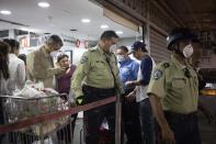 CORRECTS DAY - Police officers leave a supermarket after ordering it closed after finding costumers not wearing surgical masks to cover mouth and nose in Caracas, Venezuela, Sunday, March 15, 2020. Venezuelan President Nicolás Maduro has ordered residents in the capital of Caracas and six states to stay home under a quarantine bid to control the spread of the coronavirus. (AP Photo/Ariana Cubillos)