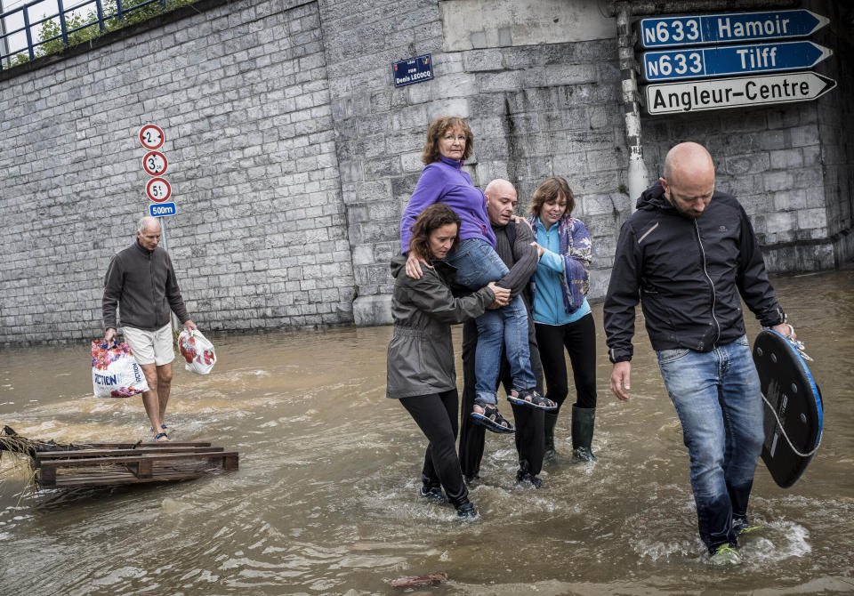 A woman is carried through a flooded street in Angleur, Province of Liege, Belgium, July 16, 2021. Severe flooding in Germany and Belgium has turned streams and streets into raging torrents that have swept away cars and caused houses to collapse. (AP Photo/Valentin Bianchi)