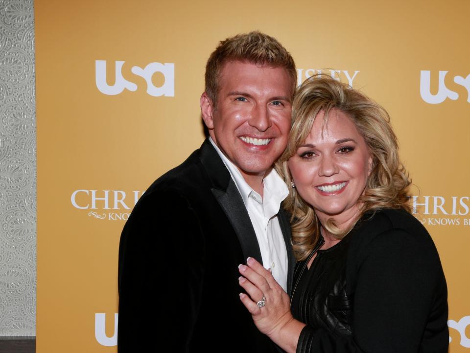 todd chrisley and julie chrisley in front of a yellow USA today sign with her hand on his chest