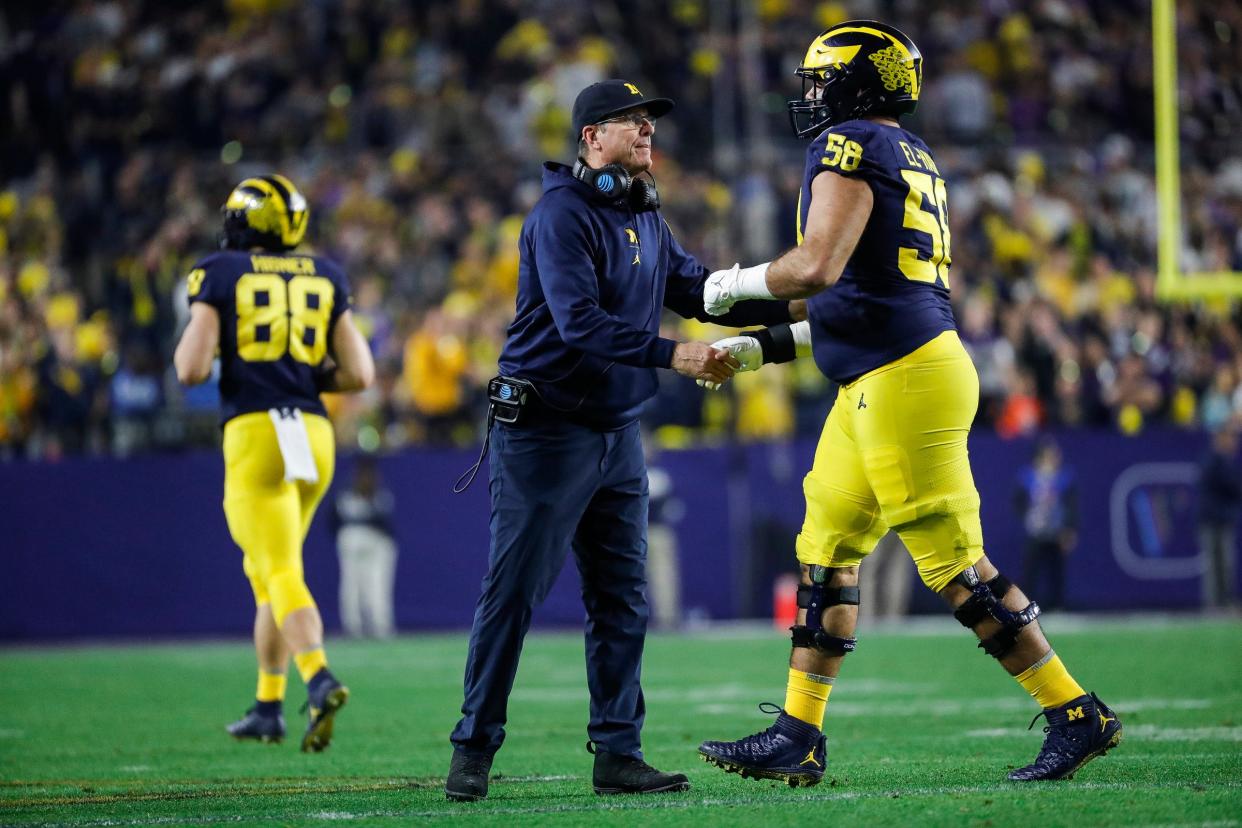 Michigan head coach Jim Harbaugh shakes hands with  offensive lineman Giovanni El-Hadi (58) after the Wolverines scored a touchdown against TCU during the second half at the Fiesta Bowl at State Farm Stadium in Glendale, Ariz. on Saturday, Dec. 31, 2022.