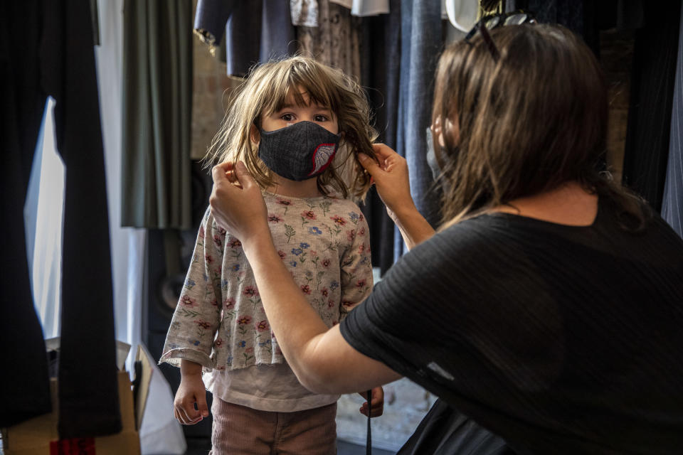 BERLIN, GERMANY - APRIL 22: A boutique shopkeeper Xana Yva Zepplin puts on a protective mask to her daughter as she prepares to open her "Rau Berlin" store for the first time since March during the novel coronavirus (COVID-19) pandemic on April 22, 2020 in Berlin, Germany. Small to midsize-shops are opening across Germany this week as state authorities follow a recommendation by the federal government to ease restrictions imposed in March meant to slow the spread of the coronavirus. Some schools are also planning to reopen soon, as are museums and hair salons in coming weeks. (Photo by Maja Hitij/Getty Images)