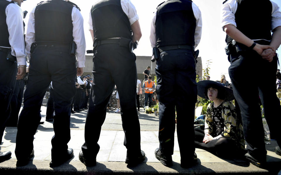 Police speak to a demonstrator on the main thoroughfare on Waterloo Bridge in central London, Saturday April 20, 2019. Climate protesters with the environmental pressure group Extinction Rebellion are once again shutting down parts of London using civic disobedience to urge residents and government to do more to protect the Earth from rising temperatures.(Victoria Jones/PA via AP)