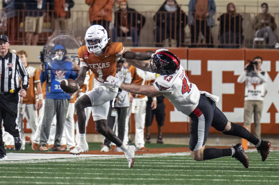 Texas' Xavier Worthy (1) avoids a tackle by Texas Tech Henry Teeter during a punt return in the second half of an NCAA college football game Friday, Nov. 24, 2023, in Austin, Texas. (AP Photo/Michael Thomas)