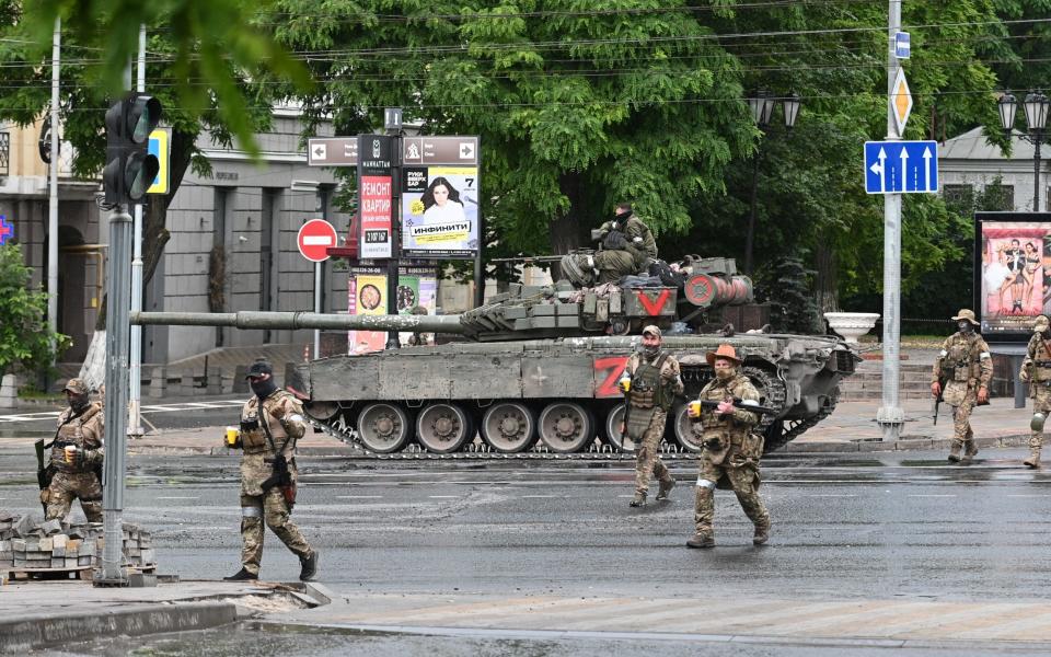 Fighters of Wagner private mercenary group cross a street as they get deployed near the headquarters of the Southern Military District in the city of Rostov-on-Don