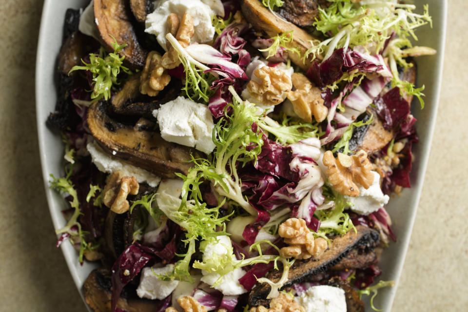 This image released by Milk Street shows a recipe for frisée and mushroom salad with goat cheese and walnuts. (Milk Street via AP)