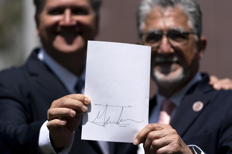 California state senators, Bob Hertzberg, left, and Anthony Portantino show a gun control bill signed by Gov. Gov. Gavin Newsom during a news conference held on on the campus of Santa Monica College in Santa Monica, Calif., Friday, July 22, 2022. Gov. Newsom signed a gun control law Friday, a month after conservative justices overturned women's constitutional right to abortions and undermined gun control laws in states including California. (AP Photo/Jae C. Hong)