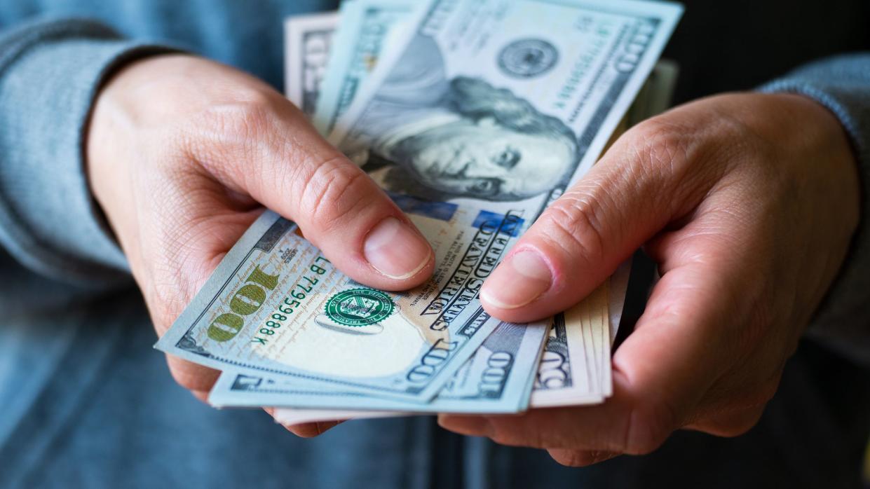 White female model shows dollar bills in her hand closeup front view