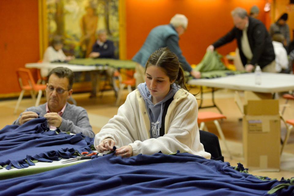 Hannah Framson, a member of the Barnstable High School military support club, right, and Dan Gervais, a member of the Rotary Club of Hyannis, work together to tie the ends on blankets. Volunteers were at First Baptist Church of Hyannis Tuesday night making blankets that will be distributed to the homeless. The blankets are part of Feel the Warmth Inc. program. To see more photos, go to www.capecodtimes.com.