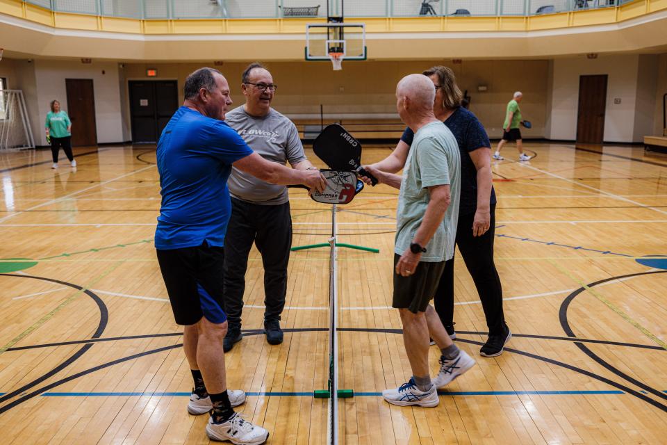 After a game of pickleball plays meet at the net and touch to congratulate each other on a game well played.